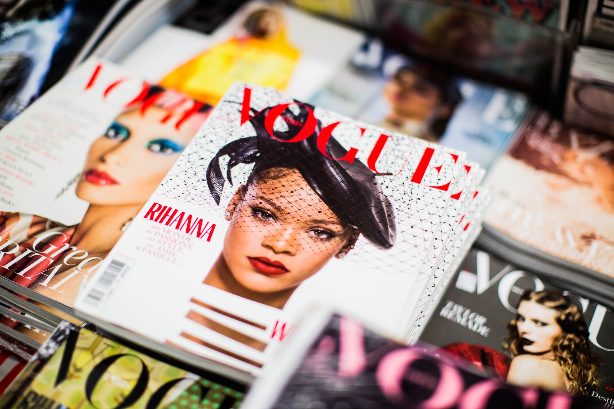 Glossy magazines stacked together featuring the Vogue cover, representing UV overprint varnish applications.