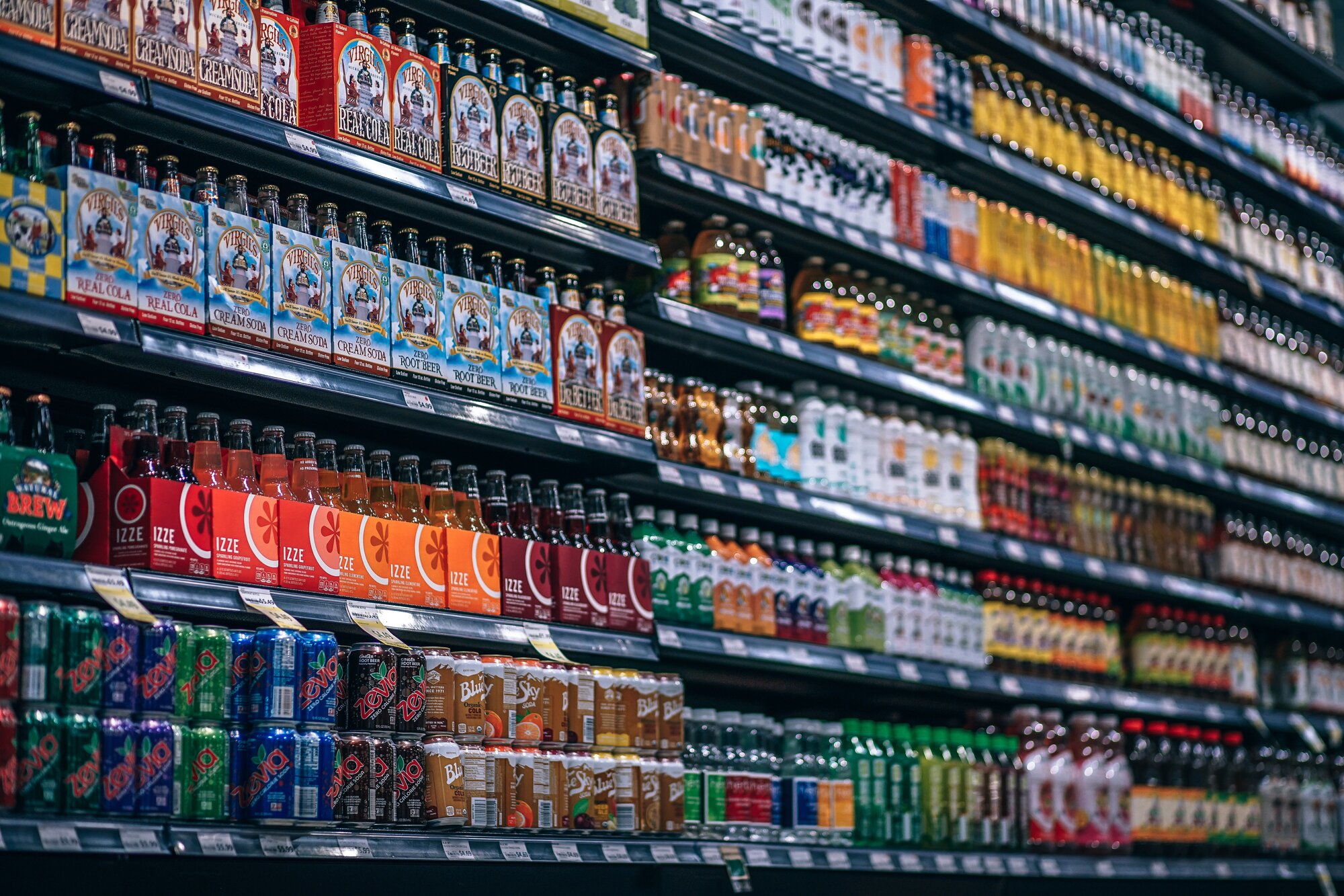 Shelves of colorful beverage bottles in a supermarket, illustrating the use of UV solutions for sensitive food and drink packaging.